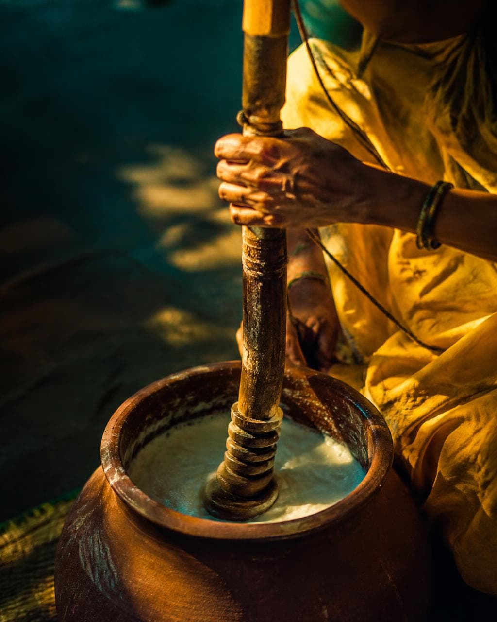 Wooden bilona churning curd into fresh white butter